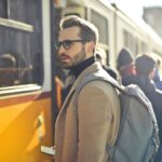 About Us A stylish man with a backpack boards a tram in bustling Budapest, Hungary, during the day.